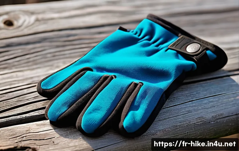등산 장갑 추천 제품 - A close-up view of a pair of high-quality winter hiking gloves lying on a rustic wooden surface outd...